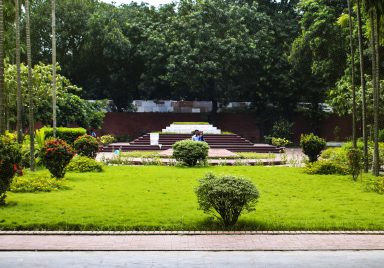 Who are the notable figures buried beside Nazrul Islam and Sharif Osman Hadi?